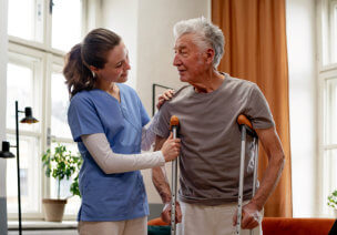 Smiling female nurse at home looking at the senior man