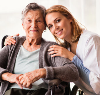 Senior woman and female nurse wearing white are smiling