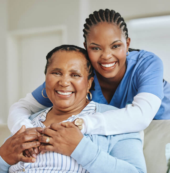 Smiling female caregiver at the back of elder woman