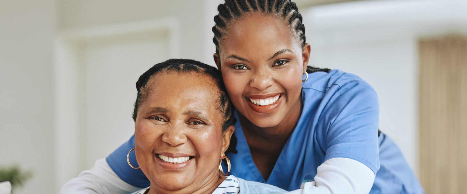 Smiling female caregiver at the back of elder woman