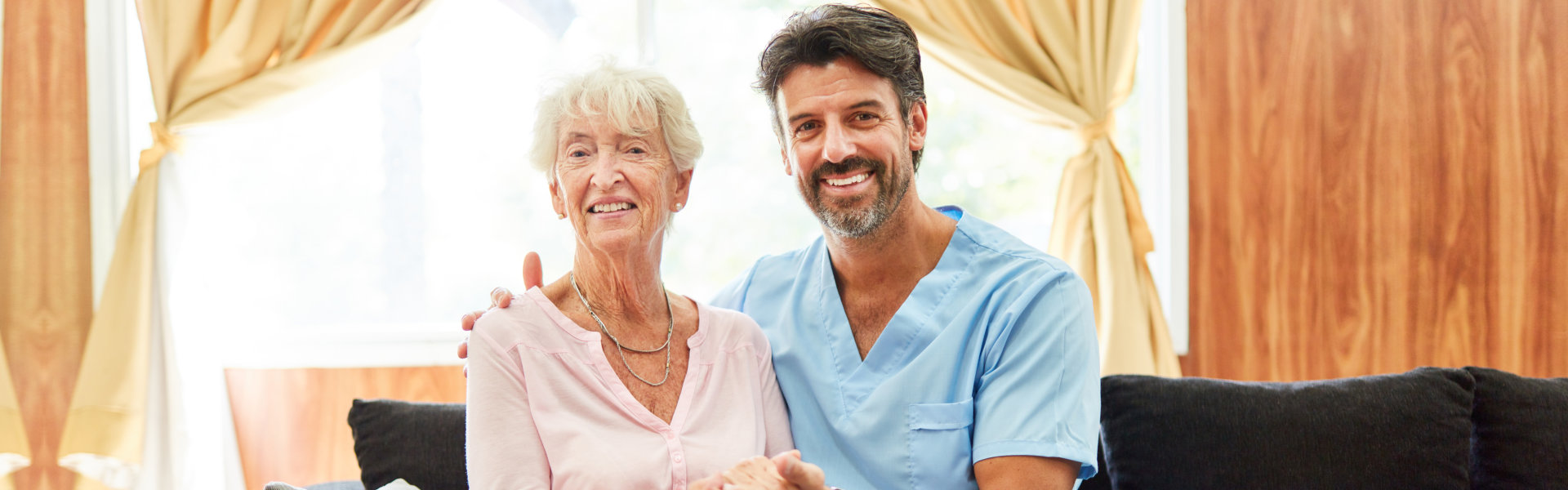 Smiling senior nurse and senior woman on a sofa