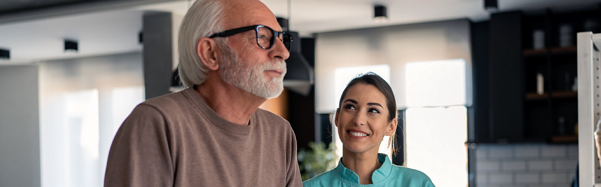 Young nurse helping senior man to walk