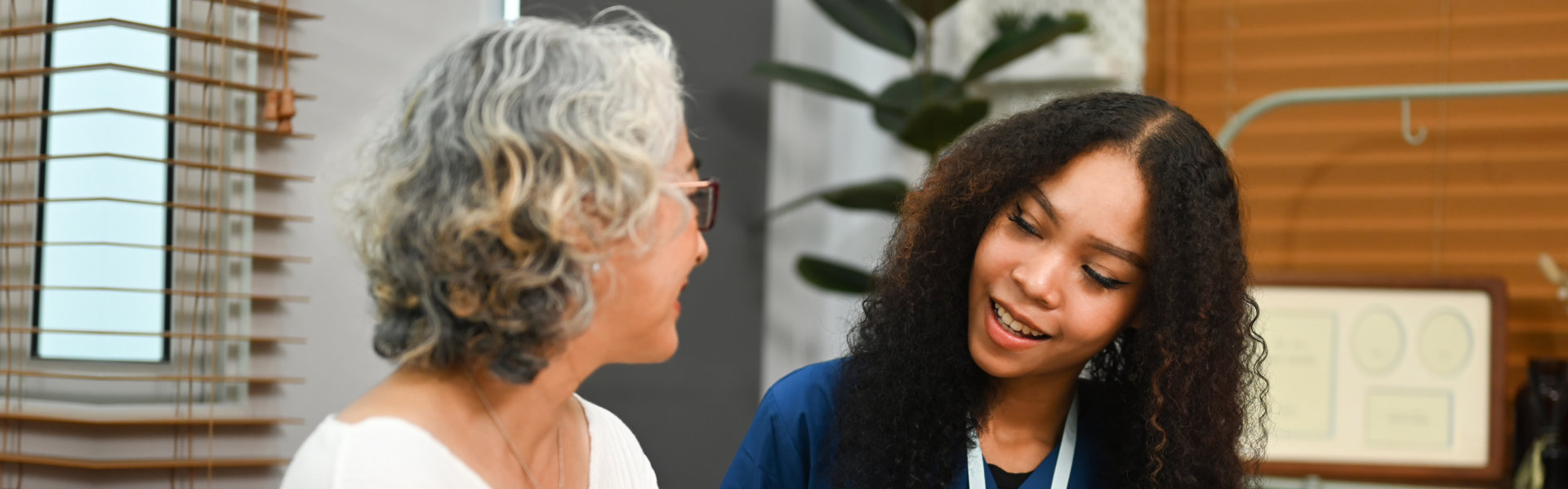 Smiling female caregiver talking to the elder woman